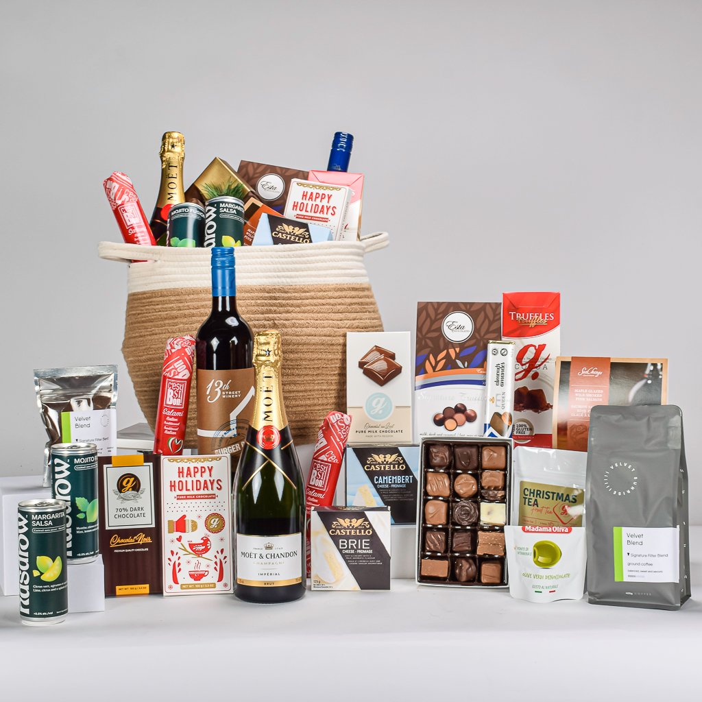 Moet Champagne 750mL and Red Canadian Wine 750mL with Assorted Reids Chocolate Box, Coffee, Tea, Maple Glazed Salmon, Salami, 2 Mocktails, Brie Cheese, Camembert, Tea, Olives, And Savoury Treats In A Two Tone White And Biege Basket