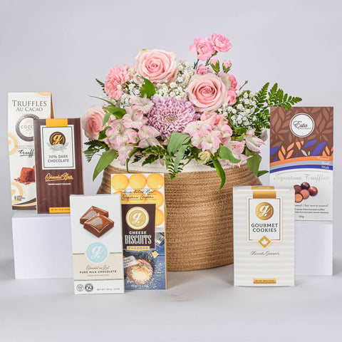 Gourmet Savoury And Sweet Items With Pink And Purple Arrangement in A Two Tone Jute Basket. 