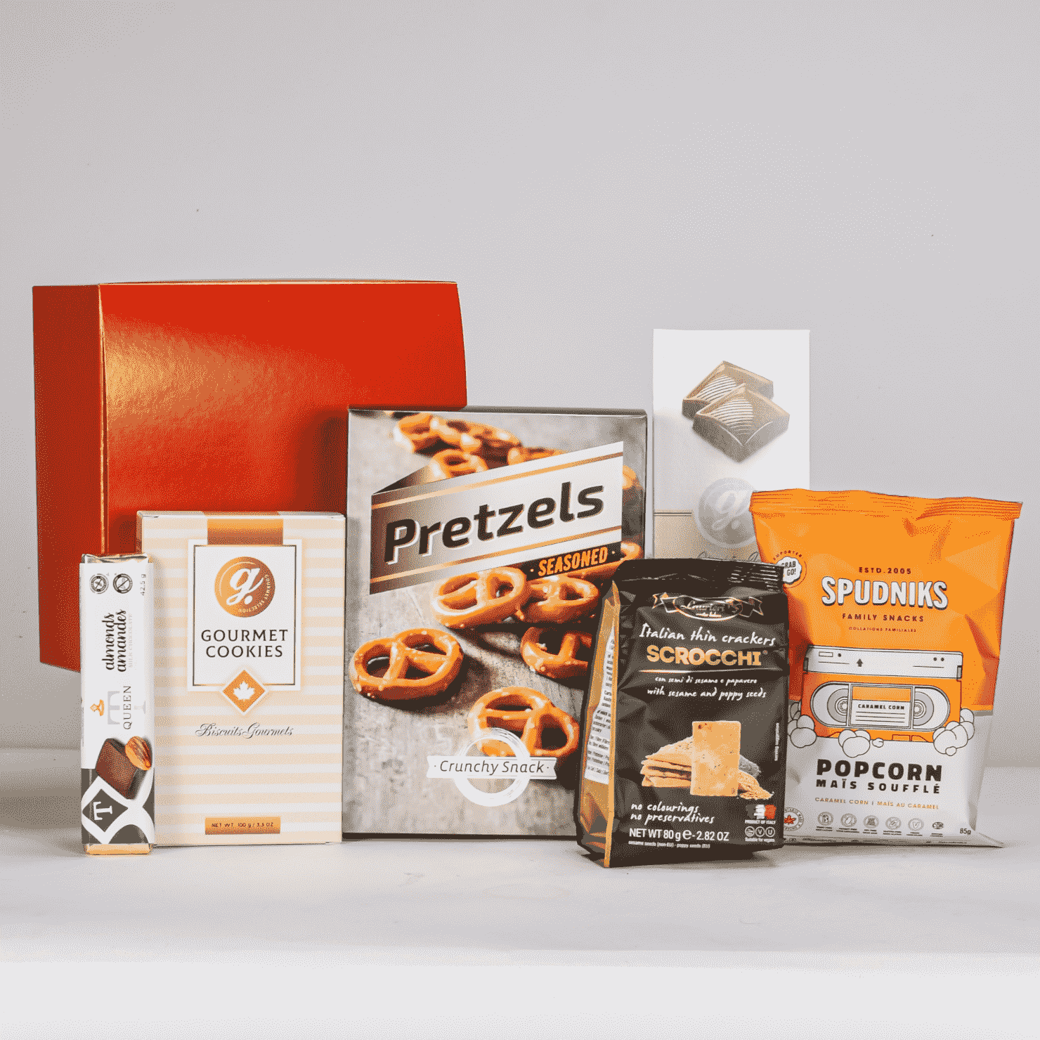 Assorted snack products including pretzels, cookies, and popcorn on a white background