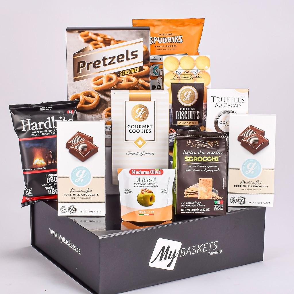 Black gift box with sweet and salty snacks including tuffles, cookeies, pretzels, chips, cheddar cookies, and olives